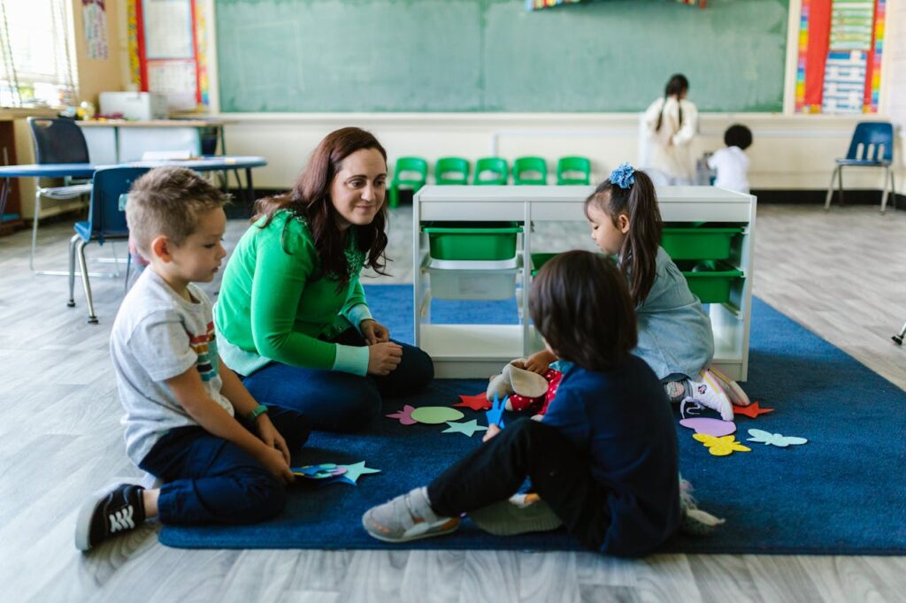 Teacher and children engaged in educational activities on a classroom floor.